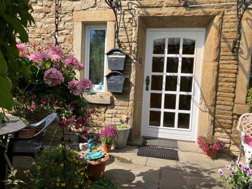 a stone house with a white door and flowers at Ferienwohnung im Grünen mit Balkon in Herdecke