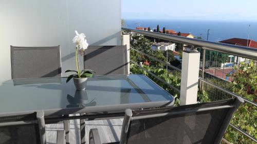 a glass table on a balcony with a flower in a vase at Alexandros Luxury Apartment in Glóssa