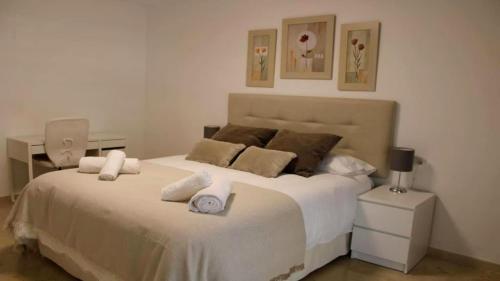 a bedroom with a large white bed with towels on it at Apartamento en Marbella junto a campos de golf in Marbella