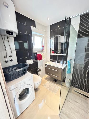 een badkamer met een wasmachine en een douche bij Holiday house "Sabine pink" in Skrbčići