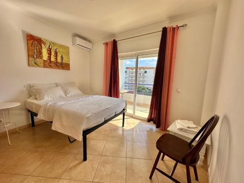 a bedroom with a bed and a window and a chair at Rei Apartment in Quarteira
