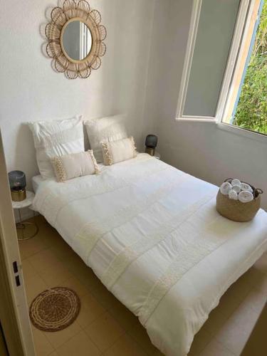 un grand lit blanc dans une chambre avec une fenêtre dans l'établissement Appartement avec terrasse en rez-de-jardin dans résidence avec piscine, tennis et aire de jeux, à Fréjus