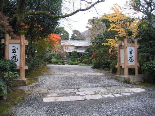 a gravel road with two gates in a garden at Gyokutei in Hakone