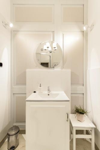 a white bathroom with a sink and a mirror at Dom Zachariasza Zappio in Gdańsk