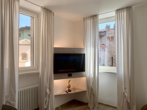 a living room with a tv and two windows at San Rocco Apartments in Riva del Garda