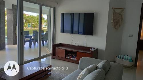 a living room with a couch and a tv on a wall at Mareazul Beachfront Resort - Casa Ancora in Playa del Carmen