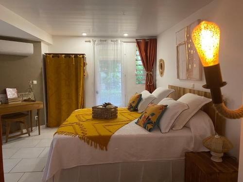 een slaapkamer met een bed met een gele deken erop bij AU PIPIRI LÉVÉ in Schœlcher