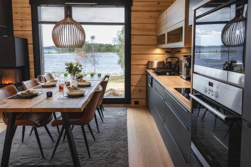 uma cozinha com mesa e cadeiras e uma cozinha com uma grande janela em Upea Villa Lapin Kulta hirsihuvila Inarijärven rannalla em Inari