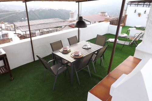 a table and chairs on a balcony with green grass at Casa Elvira in Cómpeta