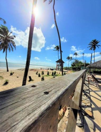 a wooden bench on a beach with palm trees at CUMBUCO - Eco Paradise - AP 112 in Caucaia