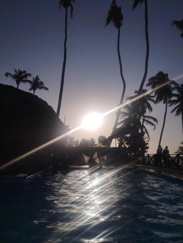 a pool with palm trees and the sun setting at CUMBUCO - Eco Paradise - AP 112 in Caucaia