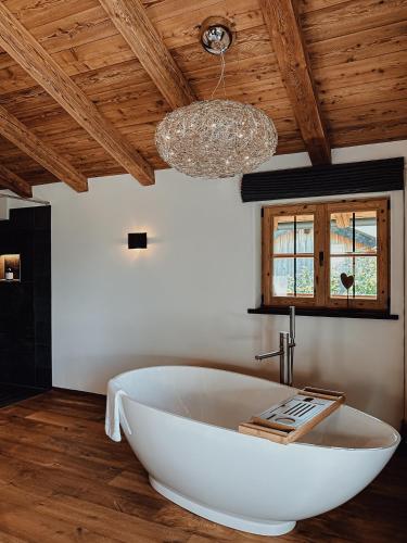 a large white bath tub in a bathroom with a chandelier at Chalet Nordic mit privatem Whirlpool und Sauna in Bayrischzell