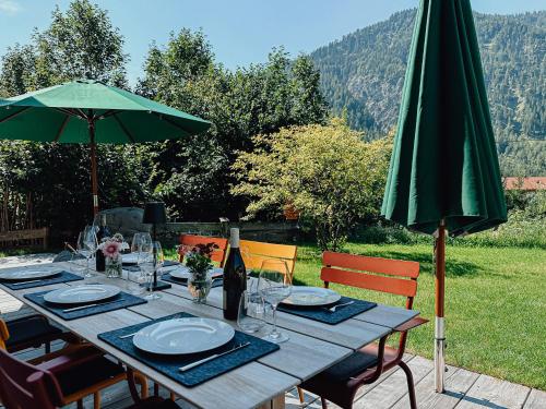 a wooden table with a green umbrella and chairs at Chalet Nordic mit privatem Whirlpool und Sauna in Bayrischzell