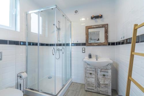 a bathroom with a glass shower and a sink at Morskie Opowieści in Niechorze