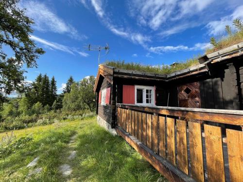 una casa de madera con una valla en un campo en Elveseter - log cabin with an amazing view, en Lunde