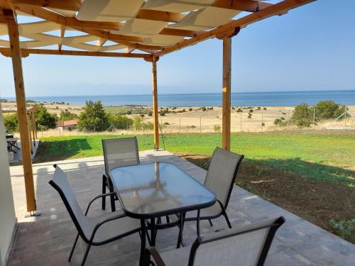 a patio with a table and chairs and the beach at Pezoulia Cottages in Samothráki