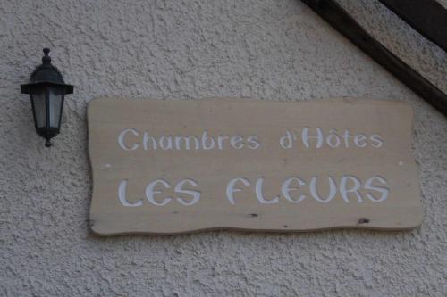 a sign on the side of a building with a lamp at Chambres D'Hotes Les Fleurs in Pila