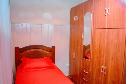 1 dormitorio con cama roja y armarios de madera en Le Bon Repos en Alta Gracia