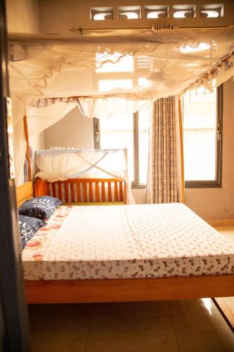 a bedroom with a canopy bed with a window at Ruhuka House - connexion STARLINK privée & gratuite in Bujumbura