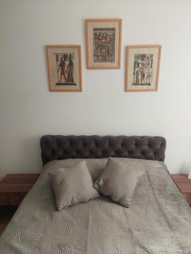 a large bed with two pictures on the wall at Apartman Todor in Veliko Gradište
