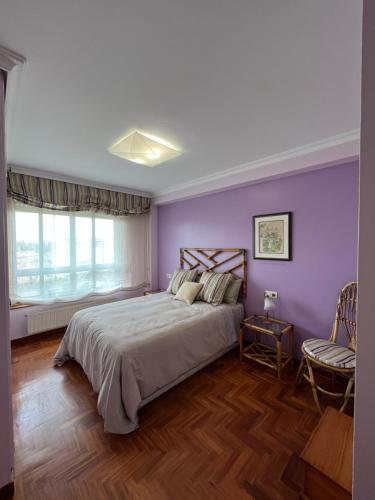 a bedroom with purple walls and a bed and a chair at Apartamento playa Vigo in Vigo