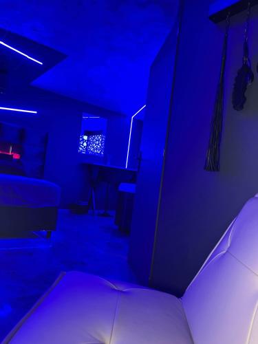een donkere kamer met een bed en een blauw licht bij Chambre romantique avec Spa B in Gruny