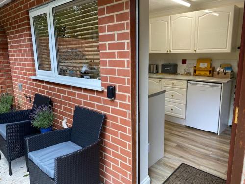 a kitchen with two chairs and a brick wall at The Nook at Tatchbury House, New Forest in Ower