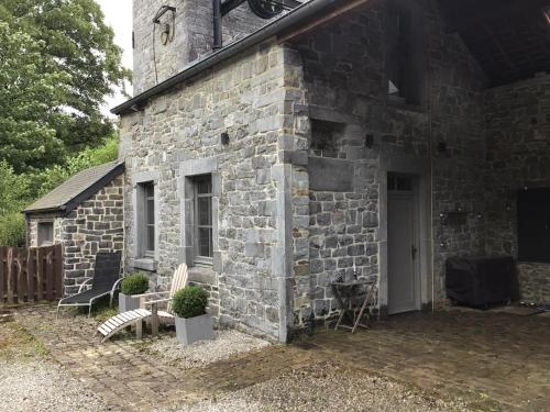 Un edificio de piedra con dos sillas delante. en L’eau et la pierre, en Yvoir