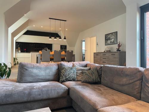 a living room with a brown couch and a kitchen at Logie De Terp in Knokke-Heist