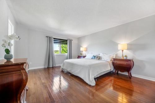 a white bedroom with a bed and a wooden floor at The house in Ottawa