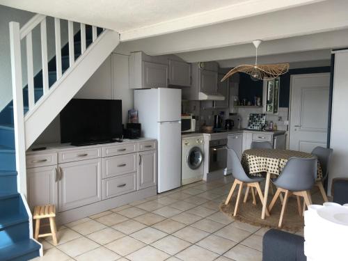 eine Küche mit weißen Schränken und einem Tisch mit Stühlen in der Unterkunft Marina / maison de pêcheur in Le Barcarès