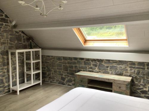 Habitación con pared de piedra, escritorio y ventana. en L’eau et la pierre, en Yvoir
