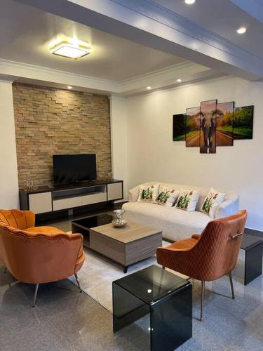 uma sala de estar com um sofá e uma televisão em Njikale Serviced Apartments - 6 em Lusaka