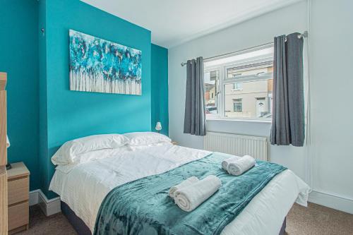 a bedroom with blue walls and a bed with towels on it at Lorne Lodge Central Swindon in Swindon