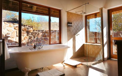 a bath tub in a bathroom with a stone wall at Shibula Solar Safari Big 5 Lodge in Welgevonden Game Reserve