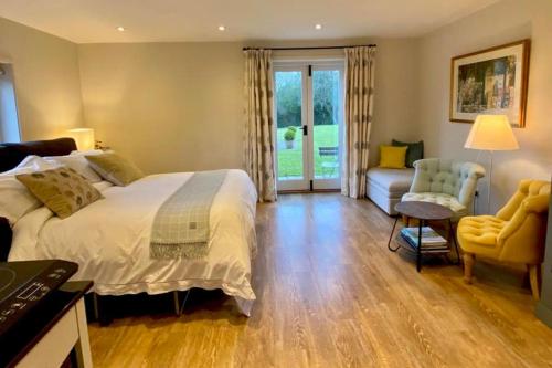a bedroom with a bed and a couch and a chair at The Annex is in the beautiful Ashdown Forest in Crowborough