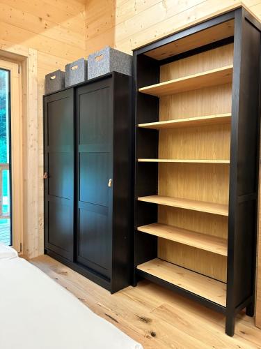 a bedroom with a black closet with wooden shelves at Das Grünhaus - Dein Chalet in Grünau im Almtal in Grünau im Almtal