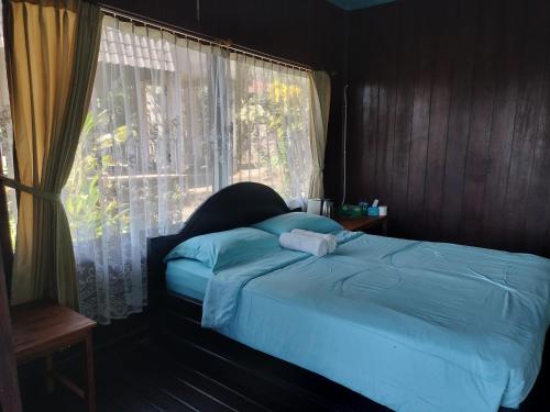 a bedroom with a blue bed with a window at D'kailash Retreat in Singaraja
