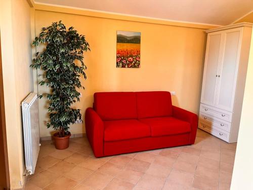 un sofá rojo en una habitación con una planta en Terrazza Cassiopea, en Capradosso
