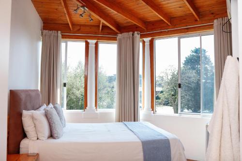 a bedroom with a bed and large windows at 57 on Lorne Guesthouse in Estcourt