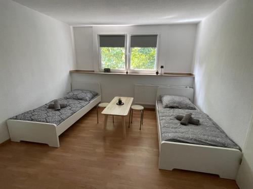 two beds in a room with a table and two windows at Günstiges Apartment Gelsenkirchen Schalke in Gelsenkirchen