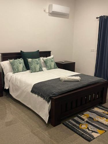 1 dormitorio con 1 cama grande con almohadas verdes en Njikale Number 3, en Lusaka