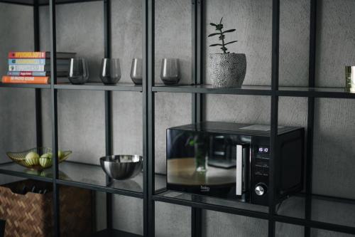 a wall with shelves with a microwave and glasses at "Quiet Center" apartment, close to train station in Tukums