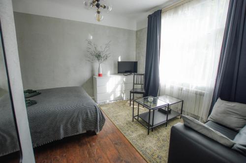 a bedroom with a bed and a couch and a television at "Quiet Center" apartment, close to train station in Tukums