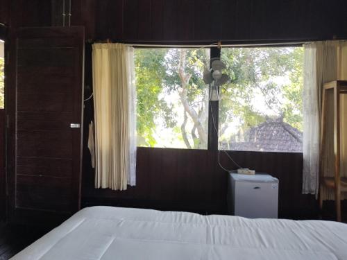 a bedroom with a bed and a large window at D'kailash Retreat in Singaraja
