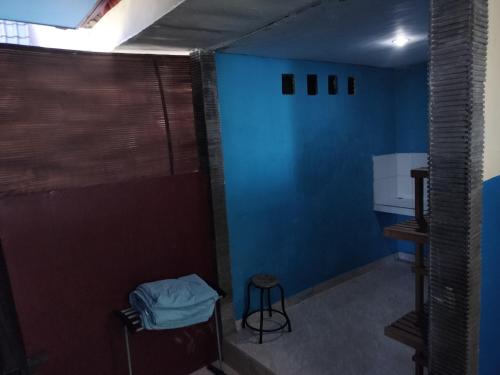a room with a blue wall and a stool at D'kailash Retreat in Singaraja