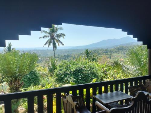 a balcony with a table and a palm tree at D'kailash Retreat in Singaraja