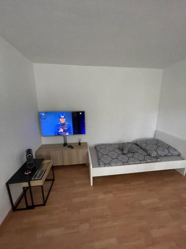 a room with a bed and a tv on a wall at Günstiges Apartment Gelsenkirchen Schalke in Gelsenkirchen