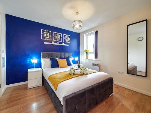 una camera con un grande letto con una parete blu di Beauchamp Suite in Coventry City Centre for Contractors Professionals Tourists Relocators Students and Family a Coventry