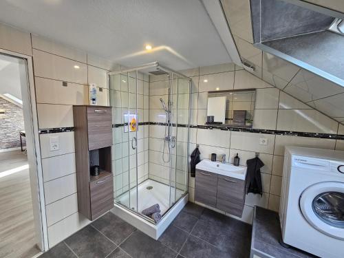 a bathroom with a shower and a sink and a washing machine at Ferienwohnung Birkenstraße in Ihlow